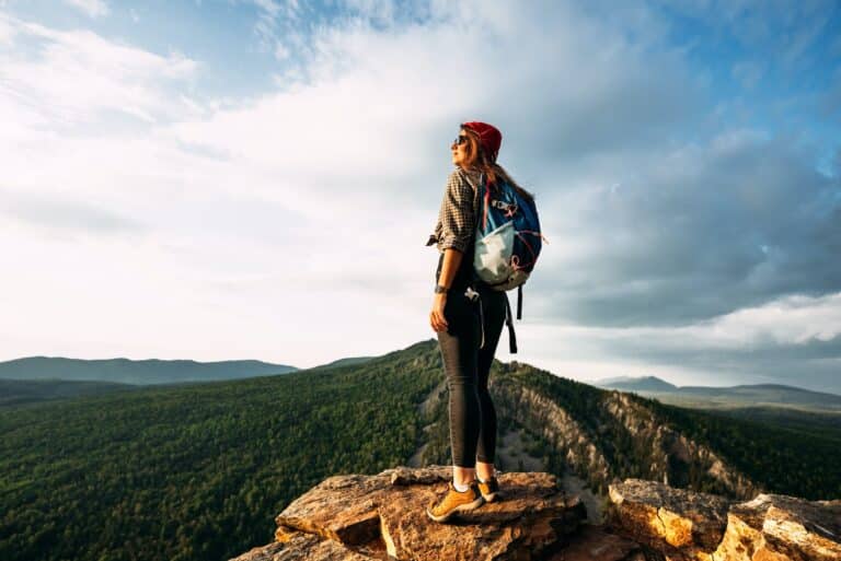 A woman meets the sunset in the mountains. Man travels in the mountains. Mountain tourism