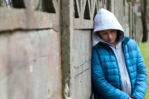 Sad teen boy 11 years old wearing gray hoodie and blue jacket in outdoors. Depressed mood.
