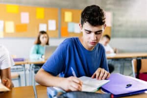 High school young student writing to notebook in class lecture